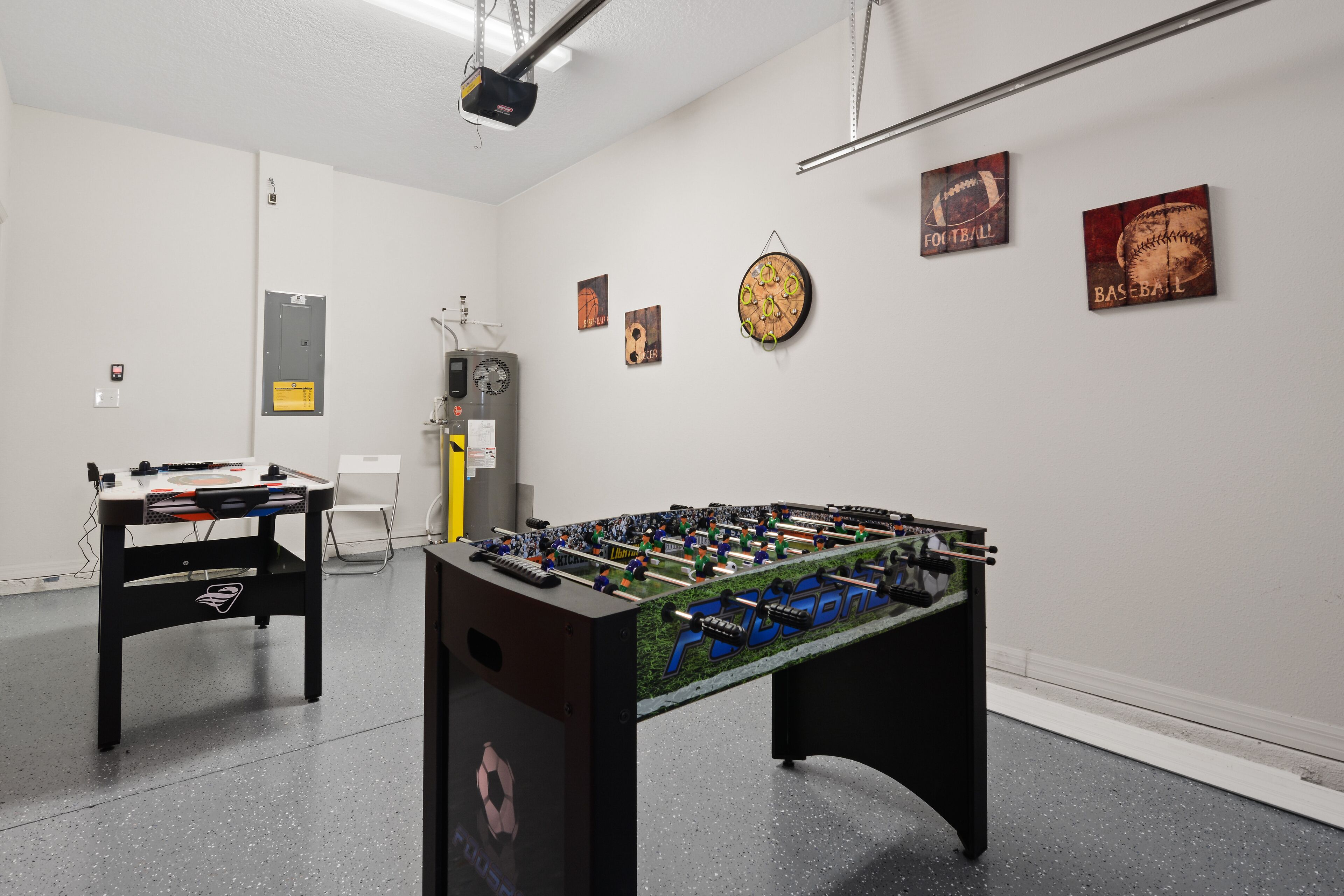 Ein Zimmer mit Kicker, einer Uhr und Wandbildern zum Thema Sport.