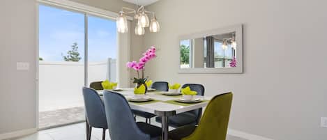 A dining area with a table set for six, six chairs, and a chandelier.