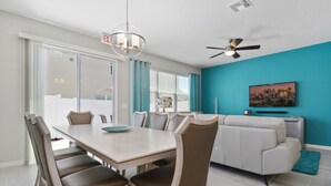 Un salon moderne comprenant un coin repas, un canapé et un ventilateur de plafond.