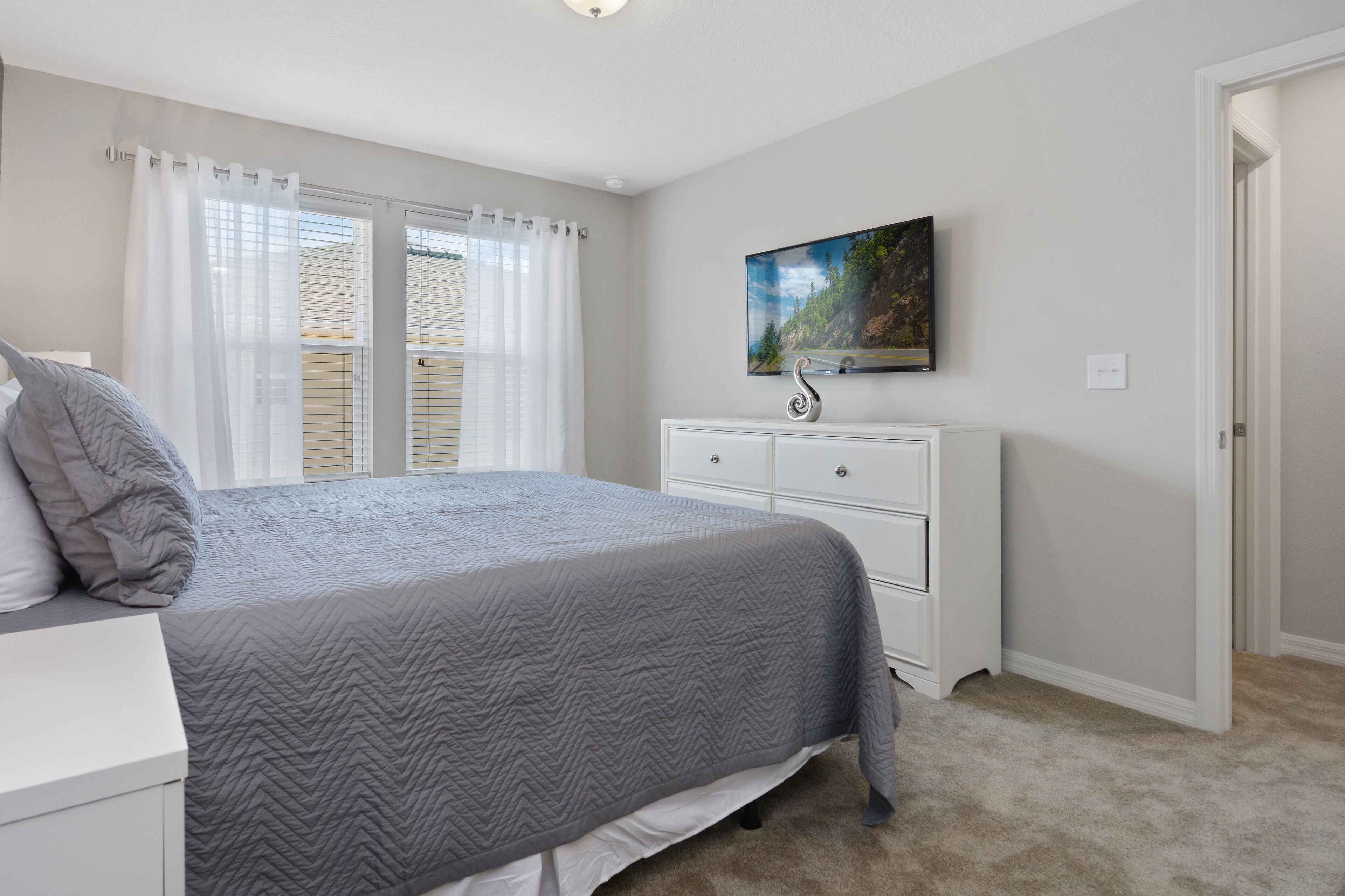 Un dormitorio con cama, cómoda, un cuadro en la pared y una puerta.