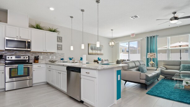 Une cuisine moderne avec des armoires blanches, des appareils en acier inoxydable et un mur d’accent de couleur turquoise.