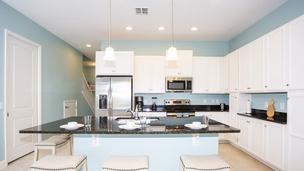 A modern kitchen with white cabinets, a central island with bar stools, stainless steel appliances, and pendant lighting. - Marvelous 4 Bedroom w/ Pool @ Festival Resort 197 (Davenport)