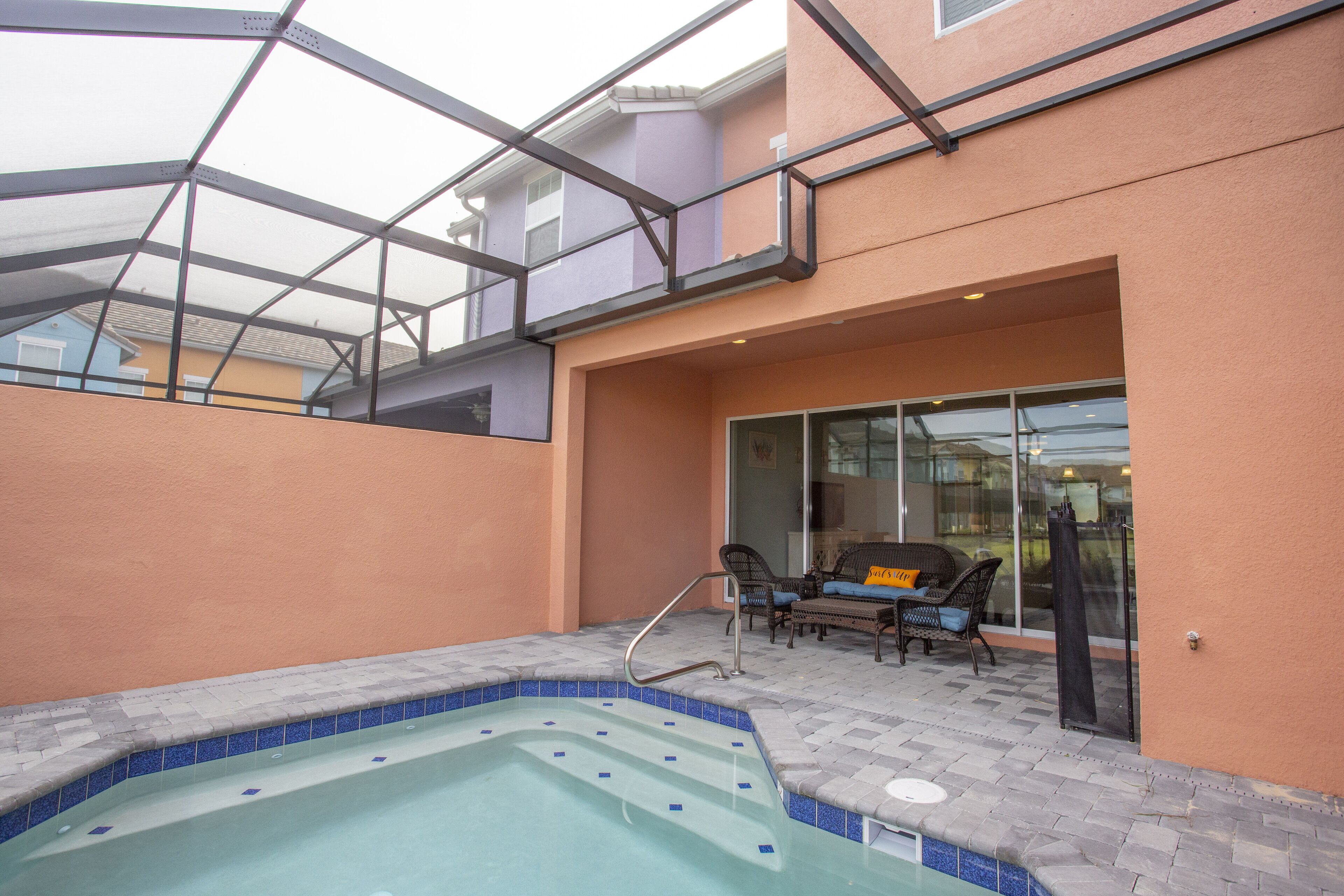 Zona de piscina en la azotea con jacuzzi, mobiliario exterior y una puerta de vidrio que da a un porche cubierto.