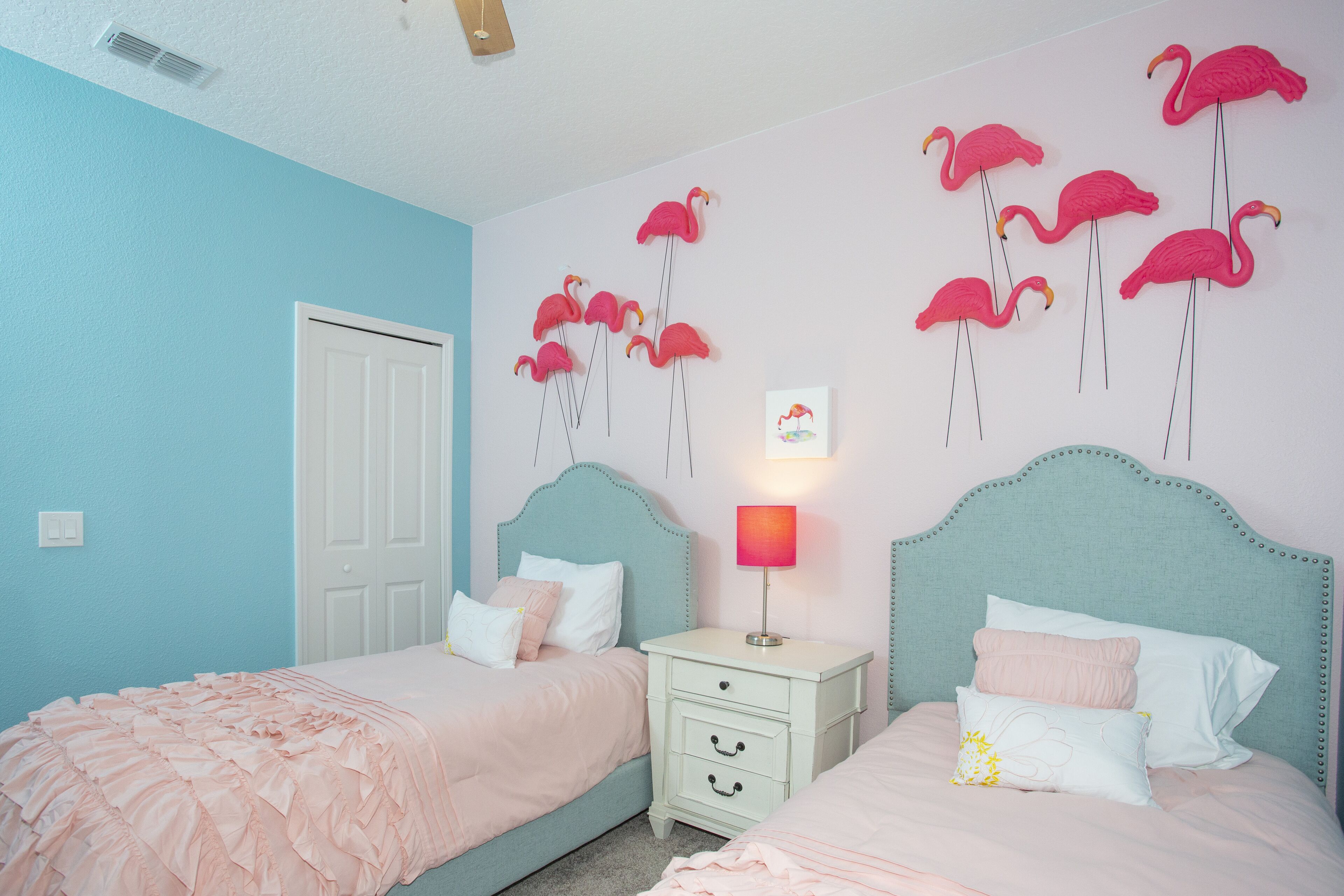 Een slaapkamer met twee bedden, een nachtkastje en een wandlamp.