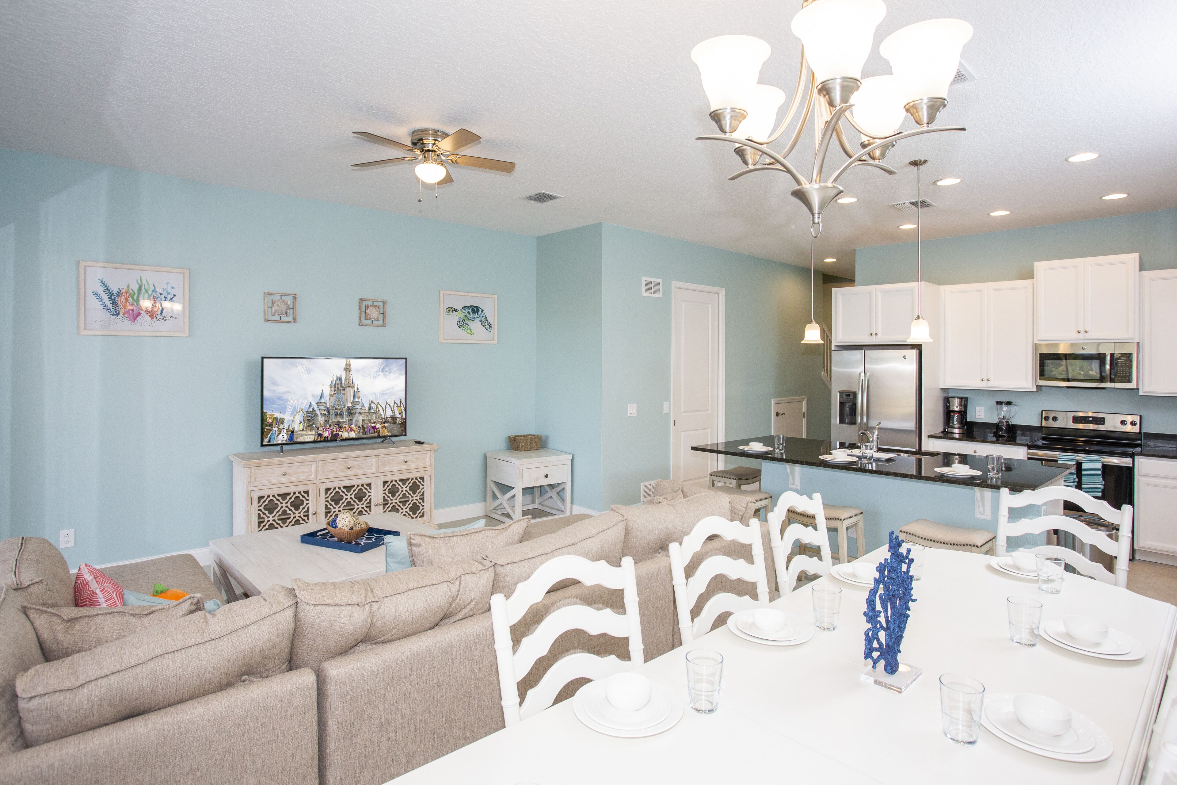 A modern living room with a sofa, TV, and dining area with chairs and a table set for a meal.