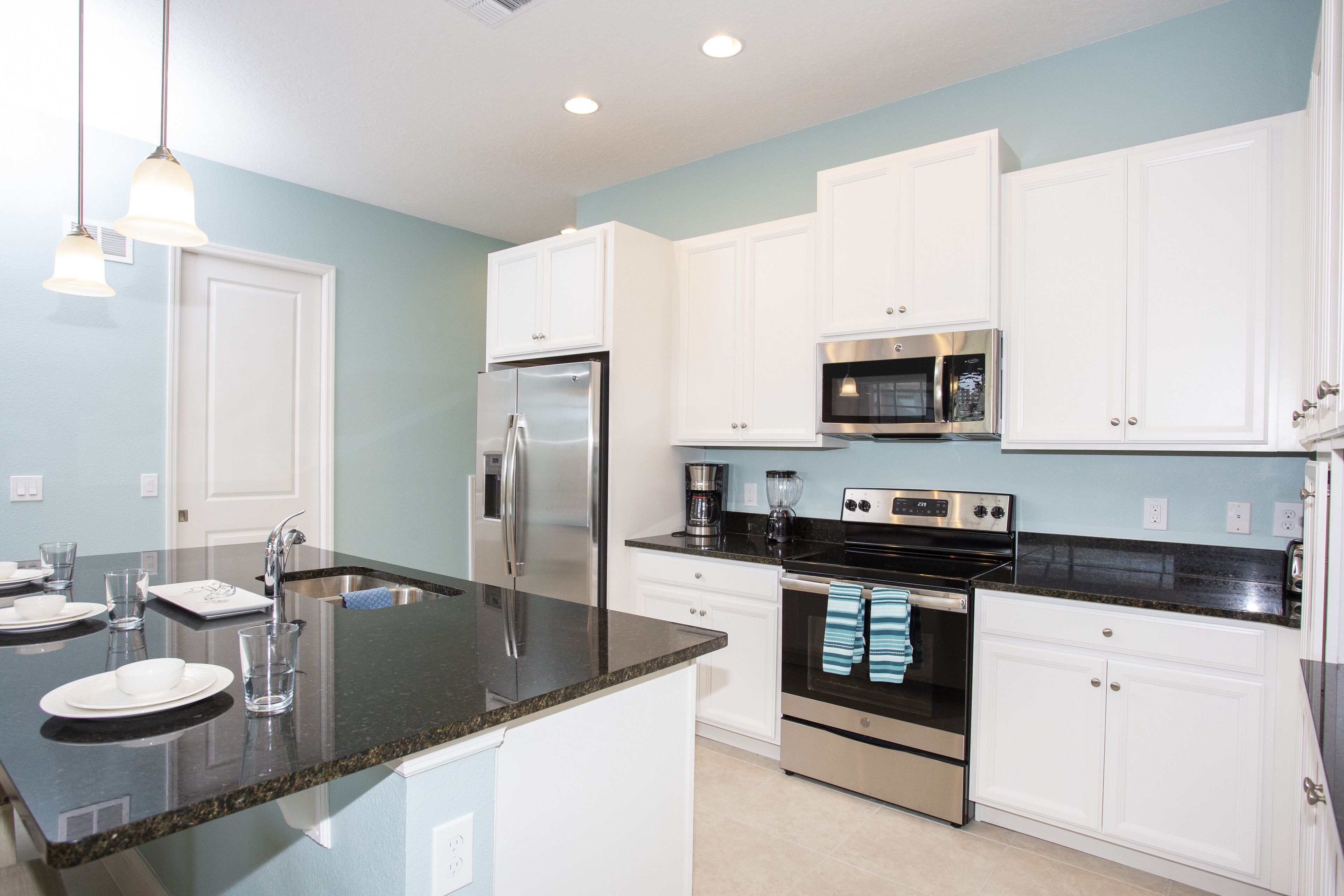 A modern kitchen with white cabinets, stainless steel appliances, and a granite countertop.
