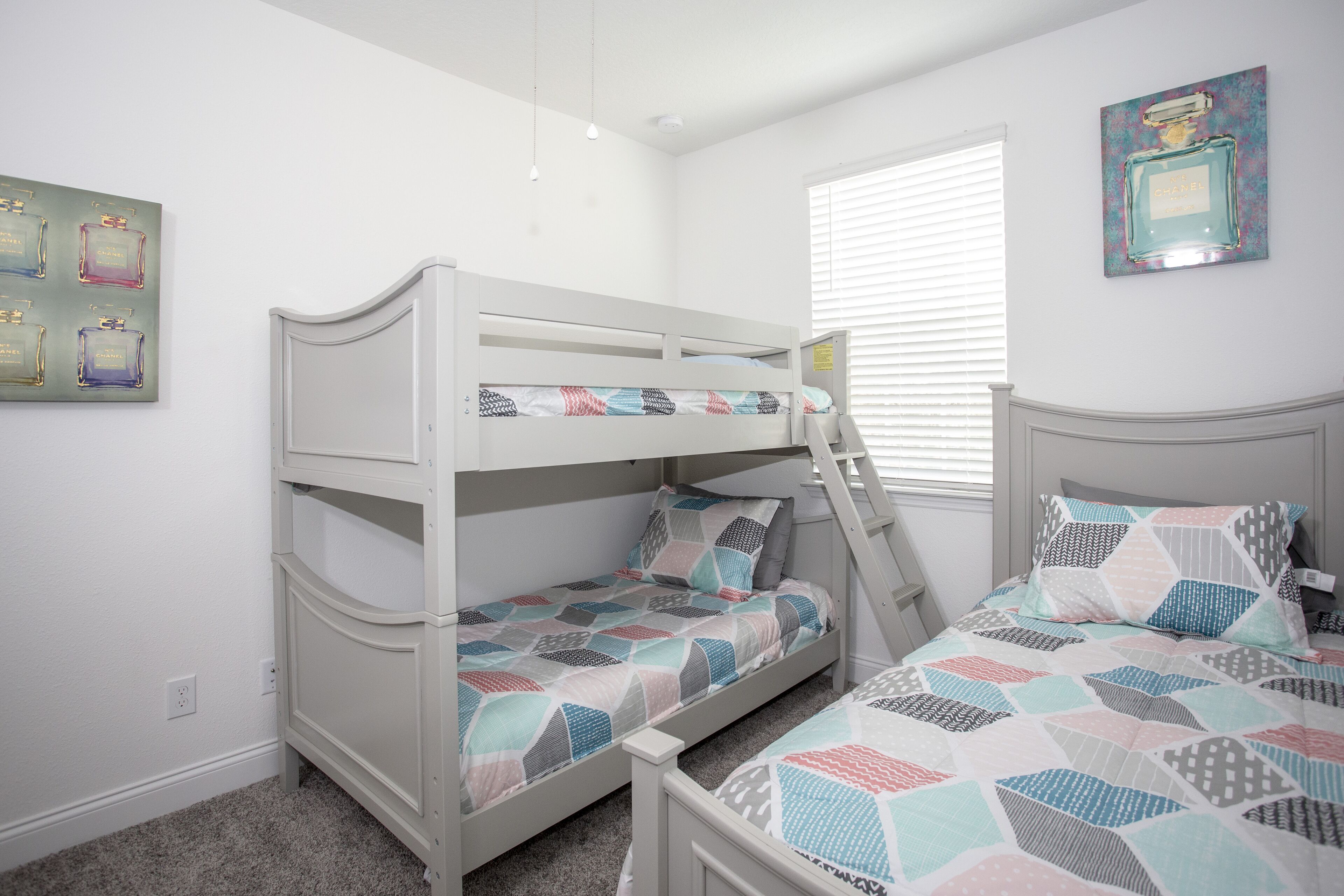 A bedroom with bunk beds, a ladder, and a window with blinds.