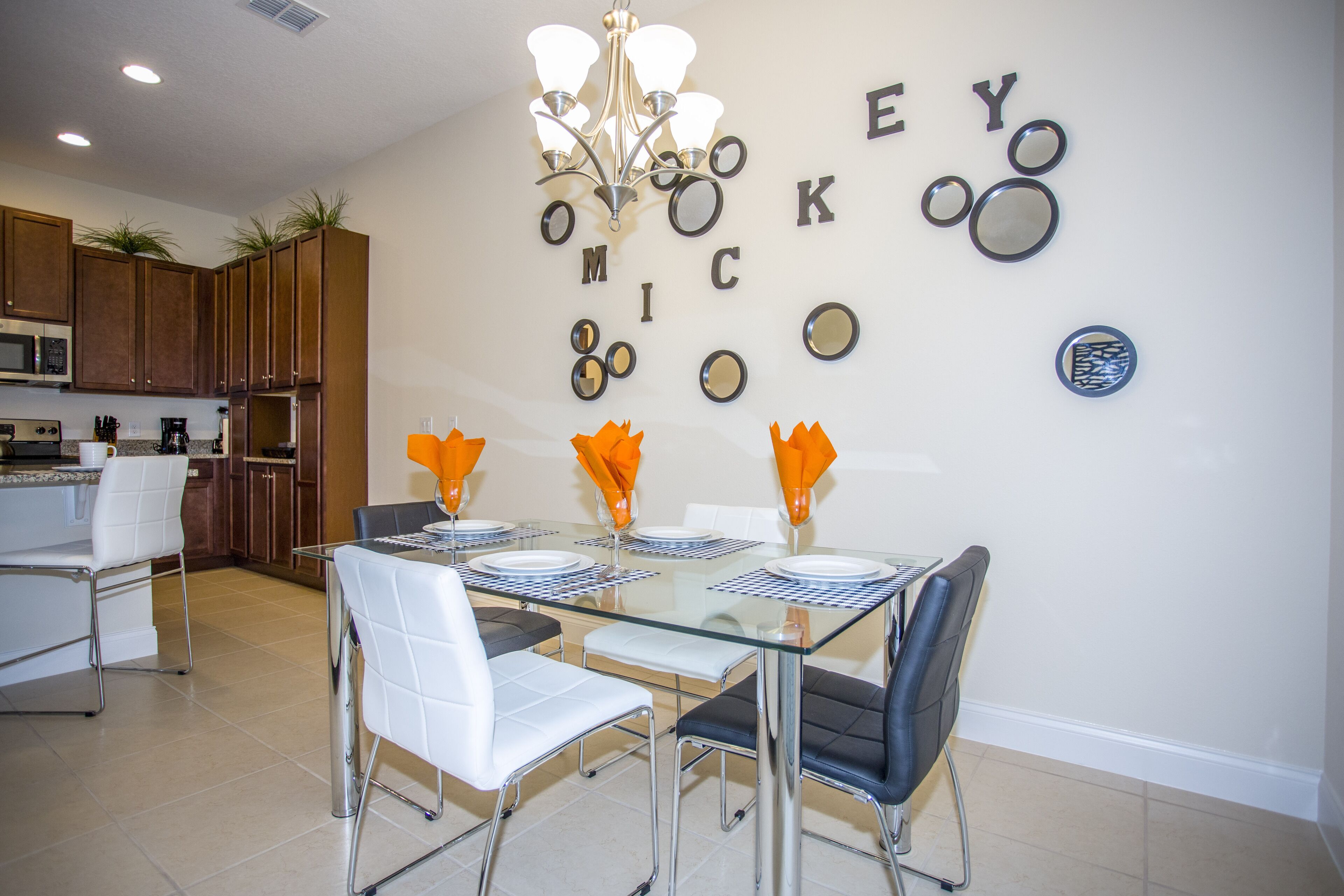 A modern kitchen with wooden cabinets, a microwave, and a dining area with a glass table and chairs.