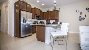 Une cuisine moderne dotée d’appareils électroménagers en acier inoxydable, de meubles en bois et d’un îlot central avec des tabourets de bar.