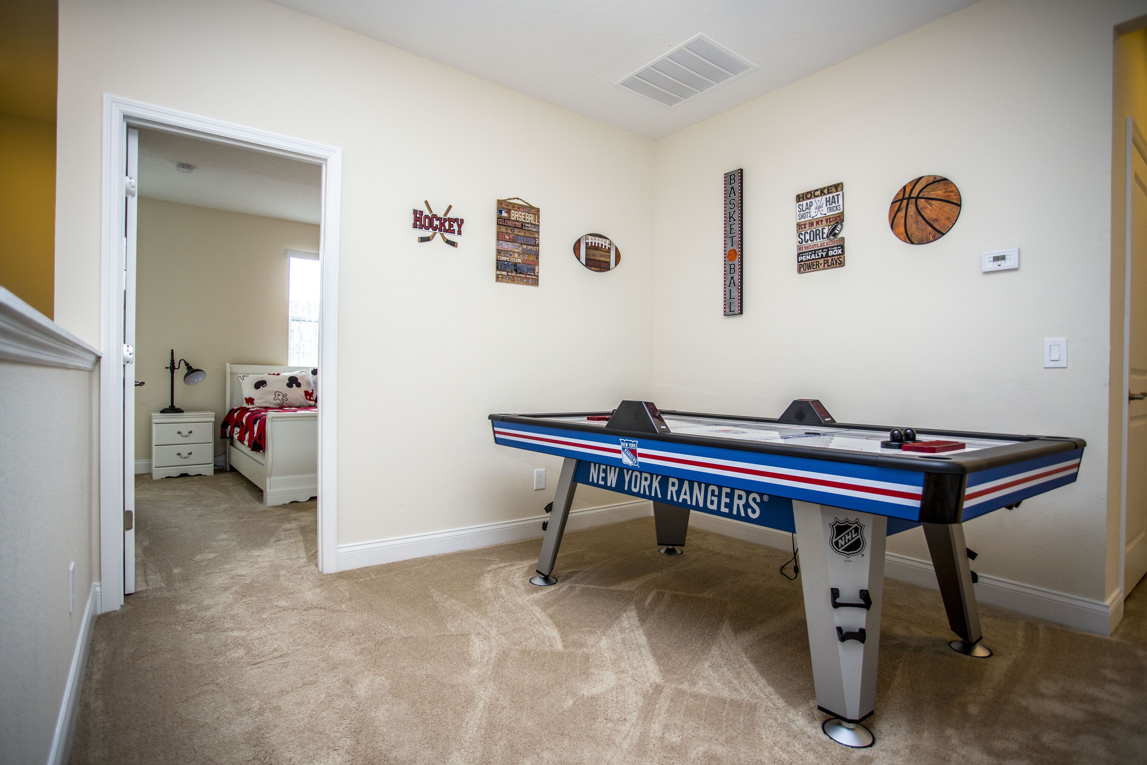 Una habitación con mesa de futbolín, una cama y recuerdos deportivos en la pared.