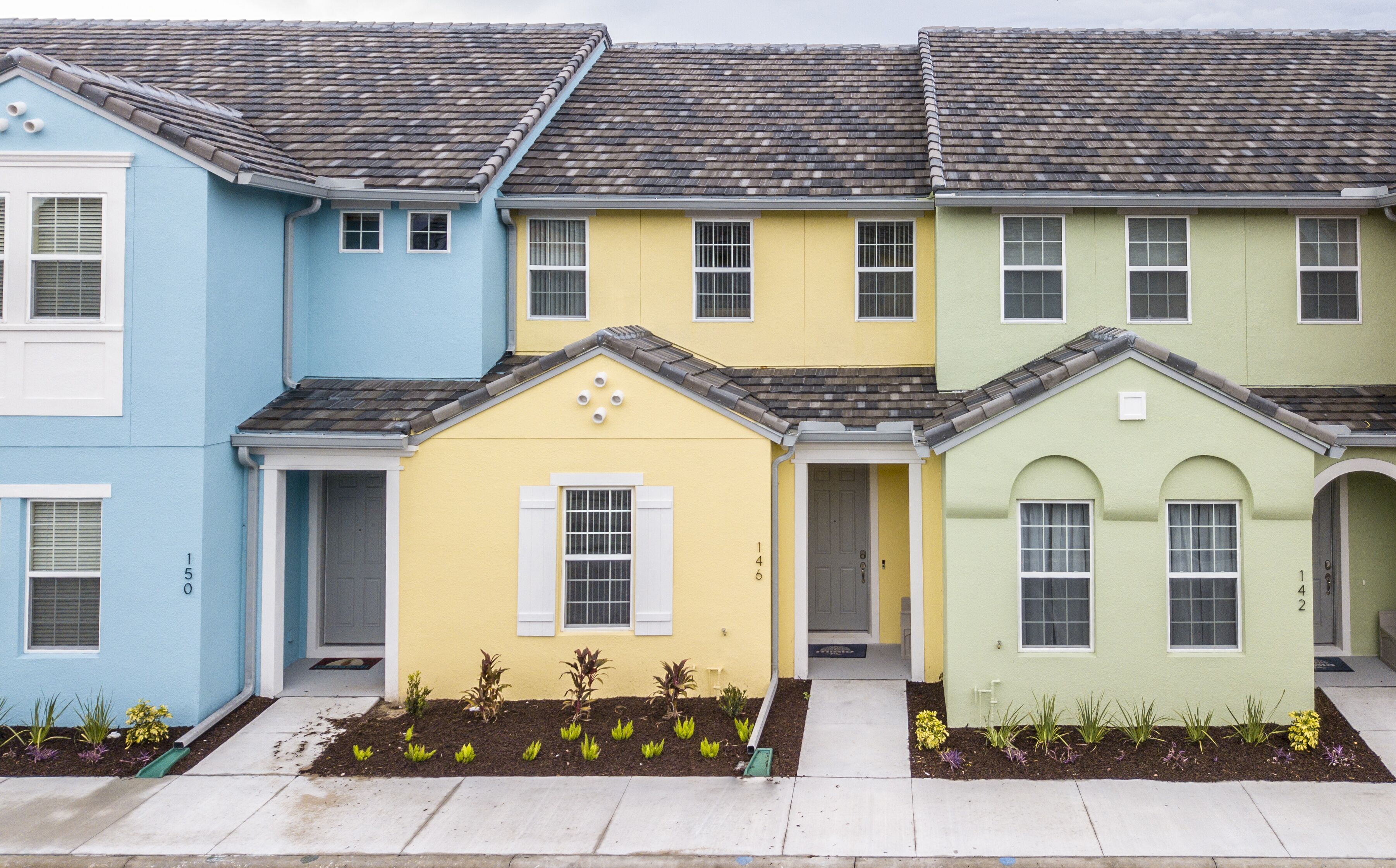 A row of three-story townhouses with a uniform architectural style, featuring a central entrance with a small porch, and a consistent roof design.