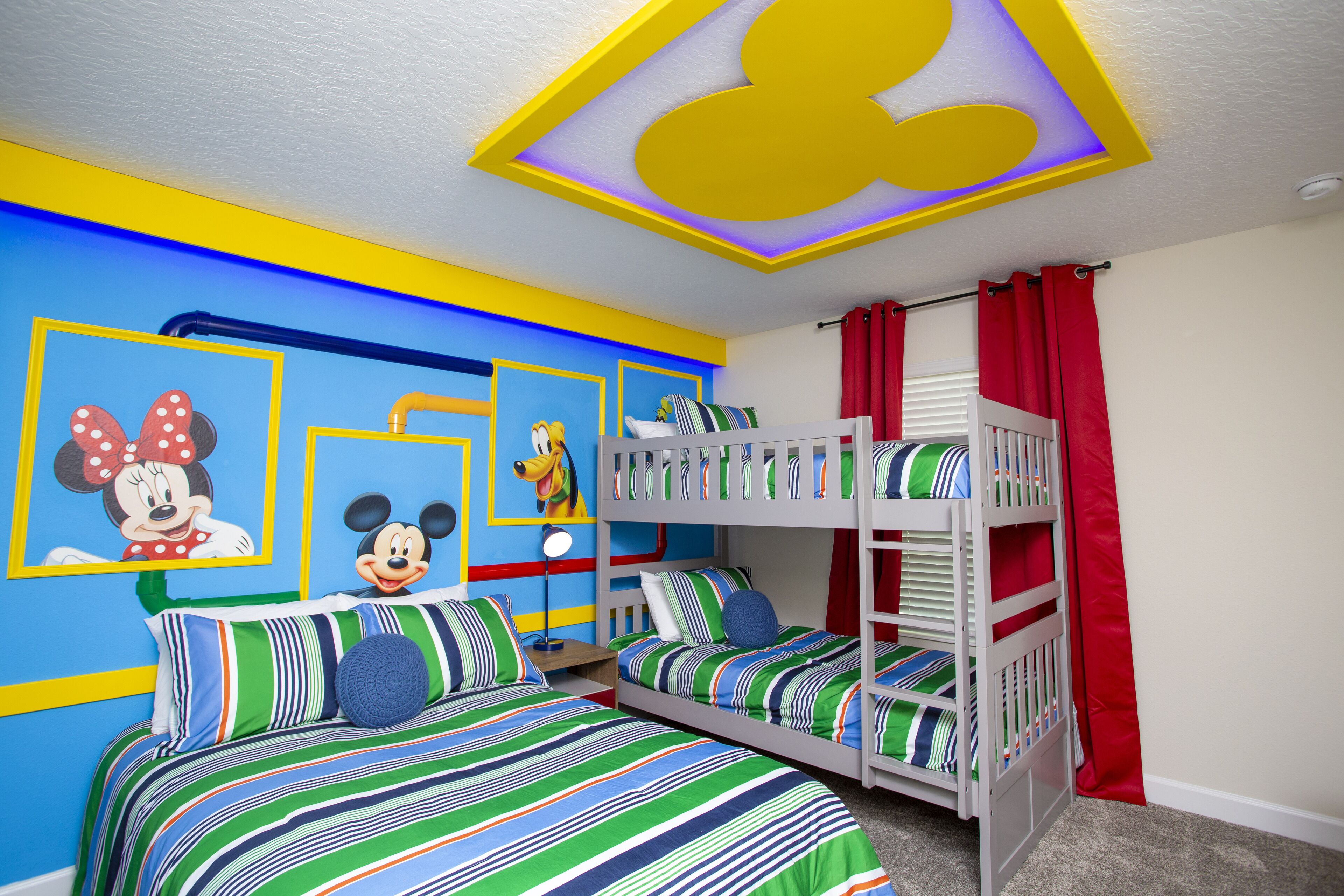 A children's room with bunk beds, colorful bedding, and Mickey Mouse and Minnie Mouse posters on the wall.
