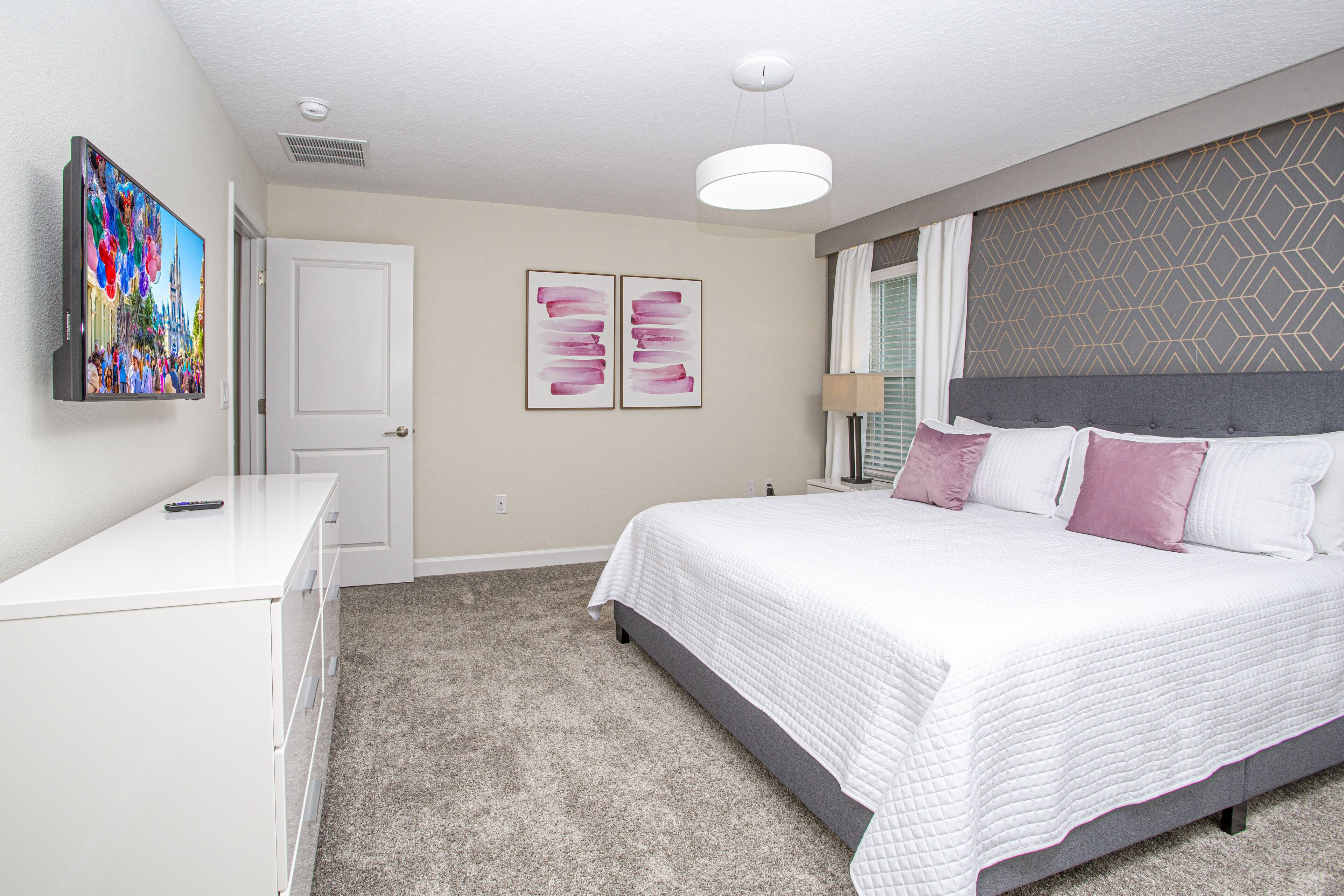 A bedroom with a bed, a dresser, a TV, and two wall art pieces.
