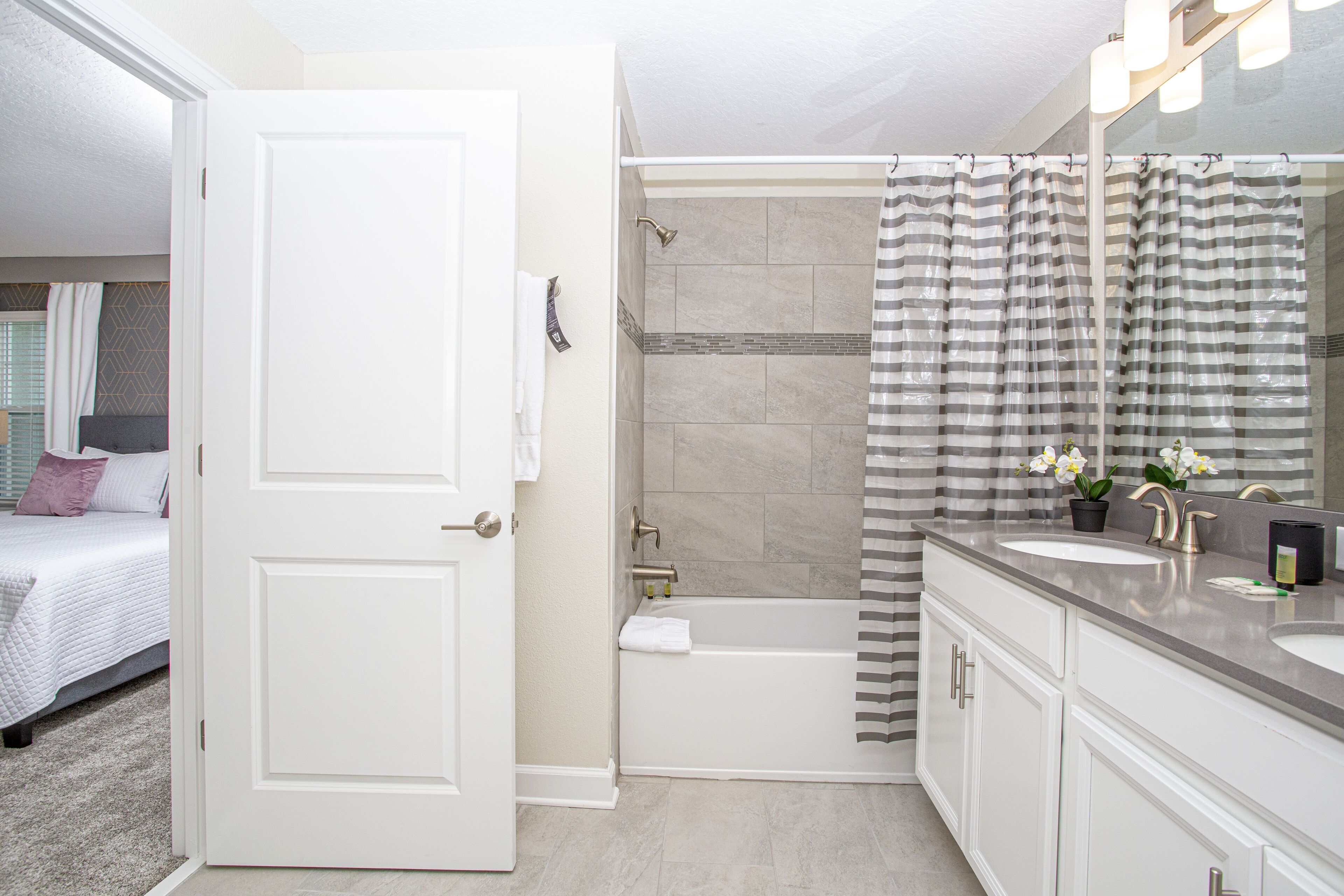 A modern bathroom with a bathtub, shower, and a large mirror.