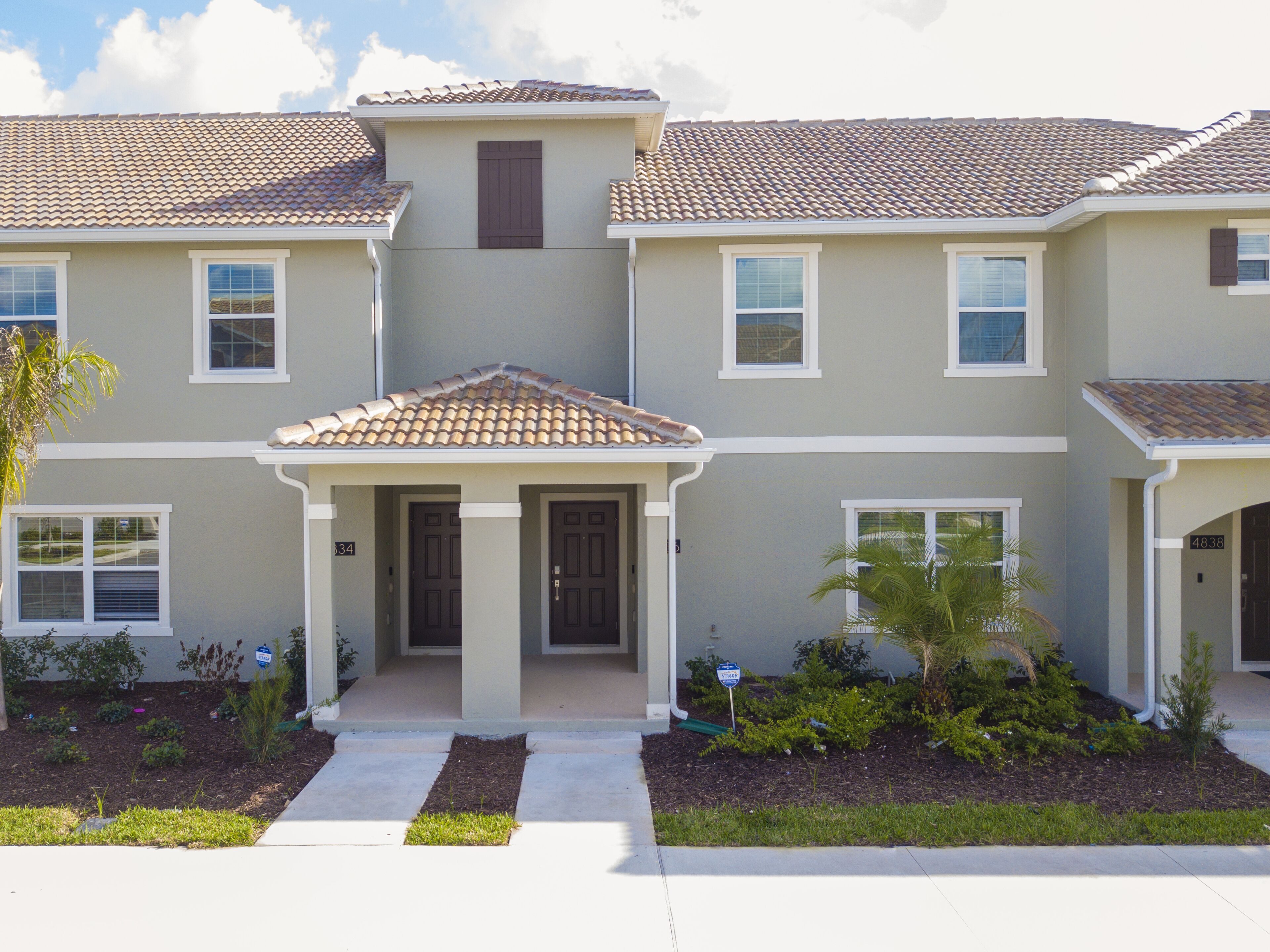 A multi-story residential building with a tiled roof, a central entrance with a door, and a small porch area.