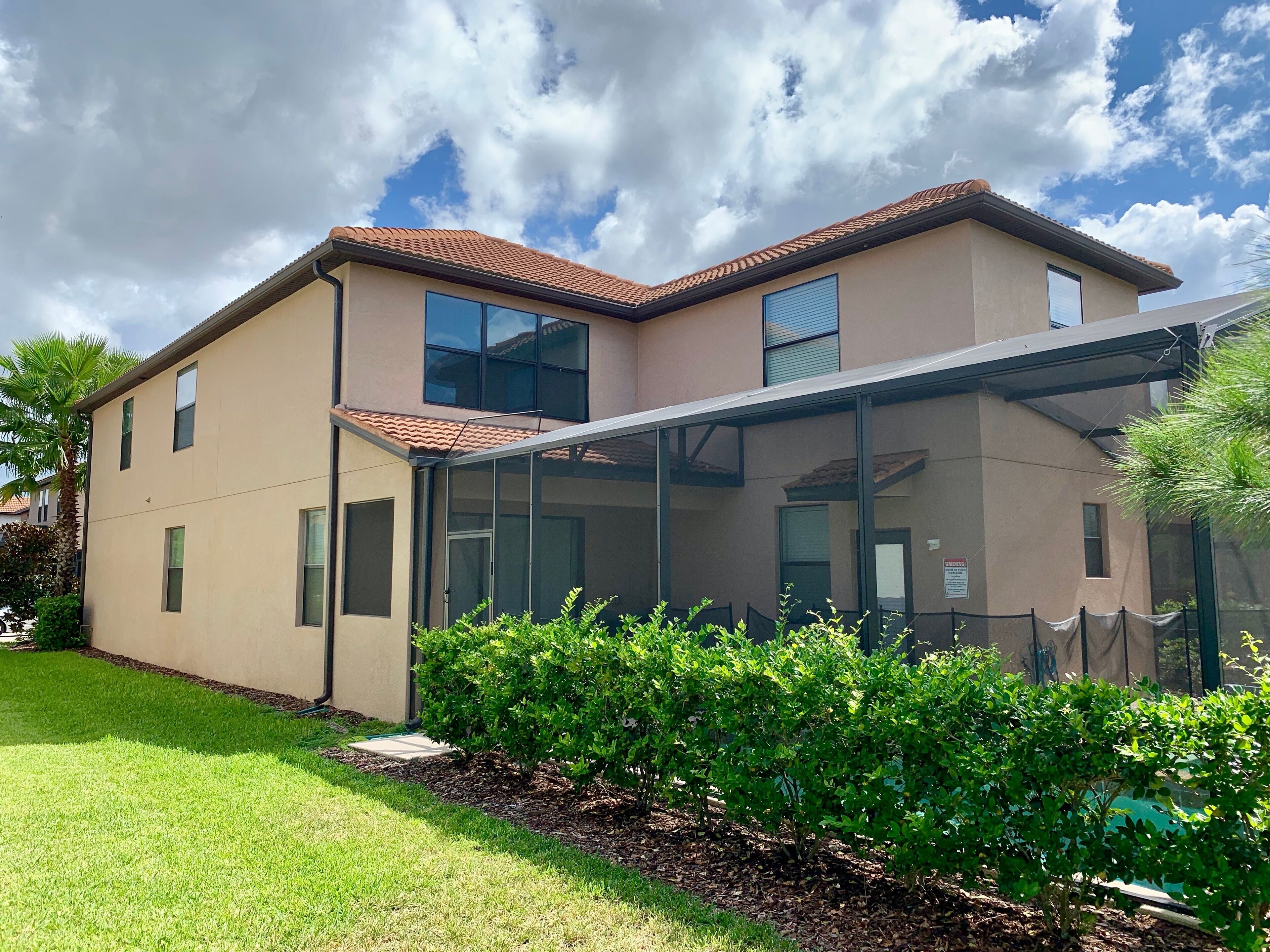 A modern two-story building with a glass conservatory, a flat roof, and a well-maintained lawn.