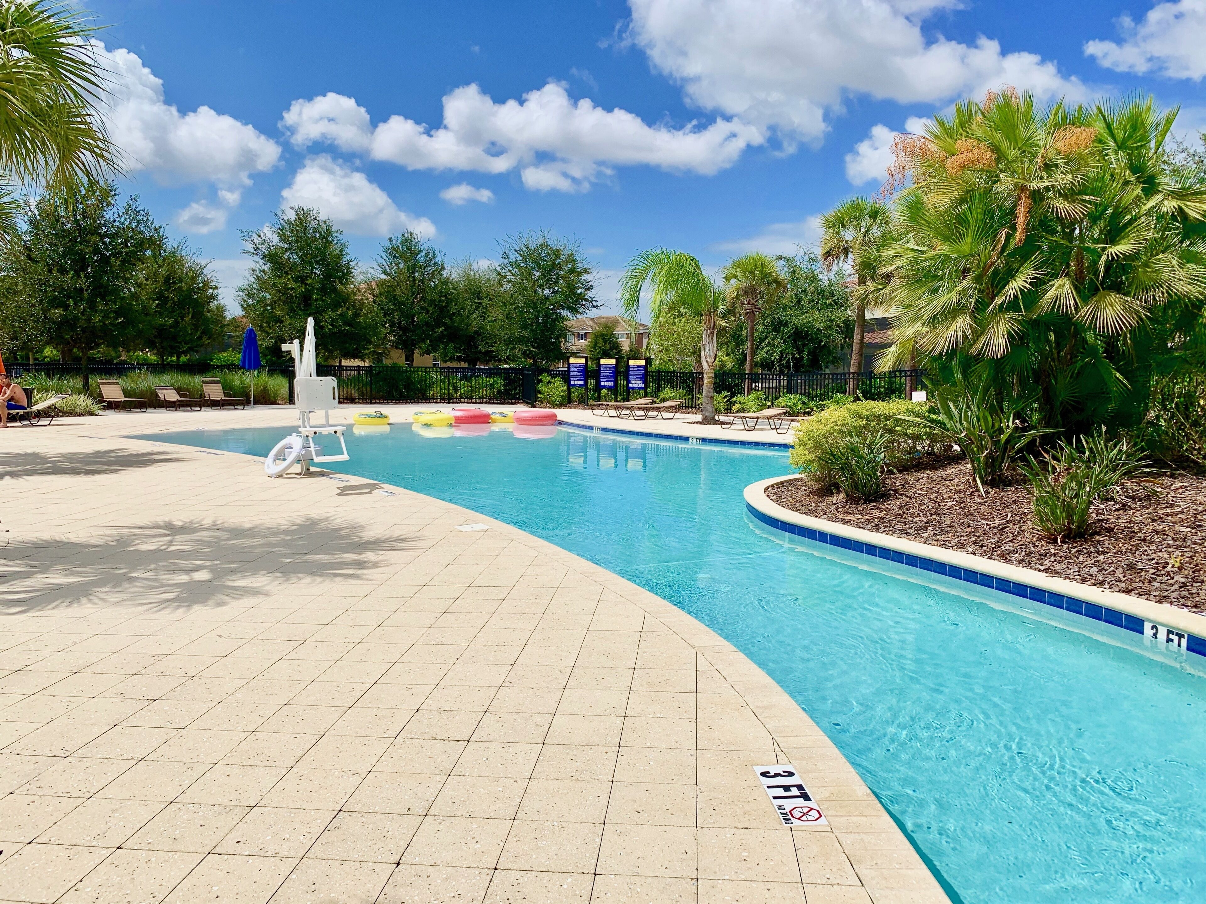 A swimming pool with a 3 FT depth limit, surrounded by palm trees and lounge chairs.