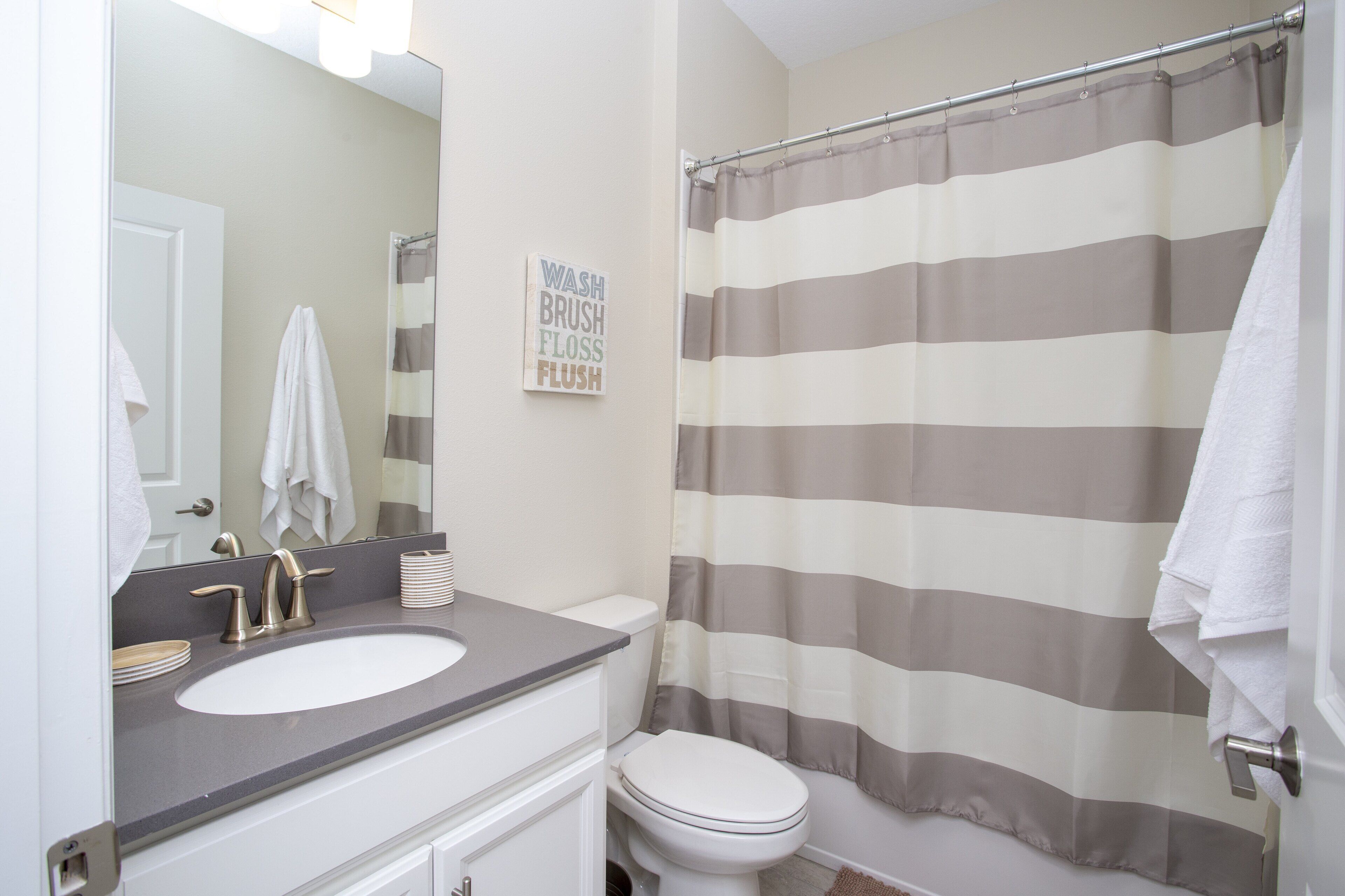 A bathroom with a striped shower curtain, a sink, and a toilet.