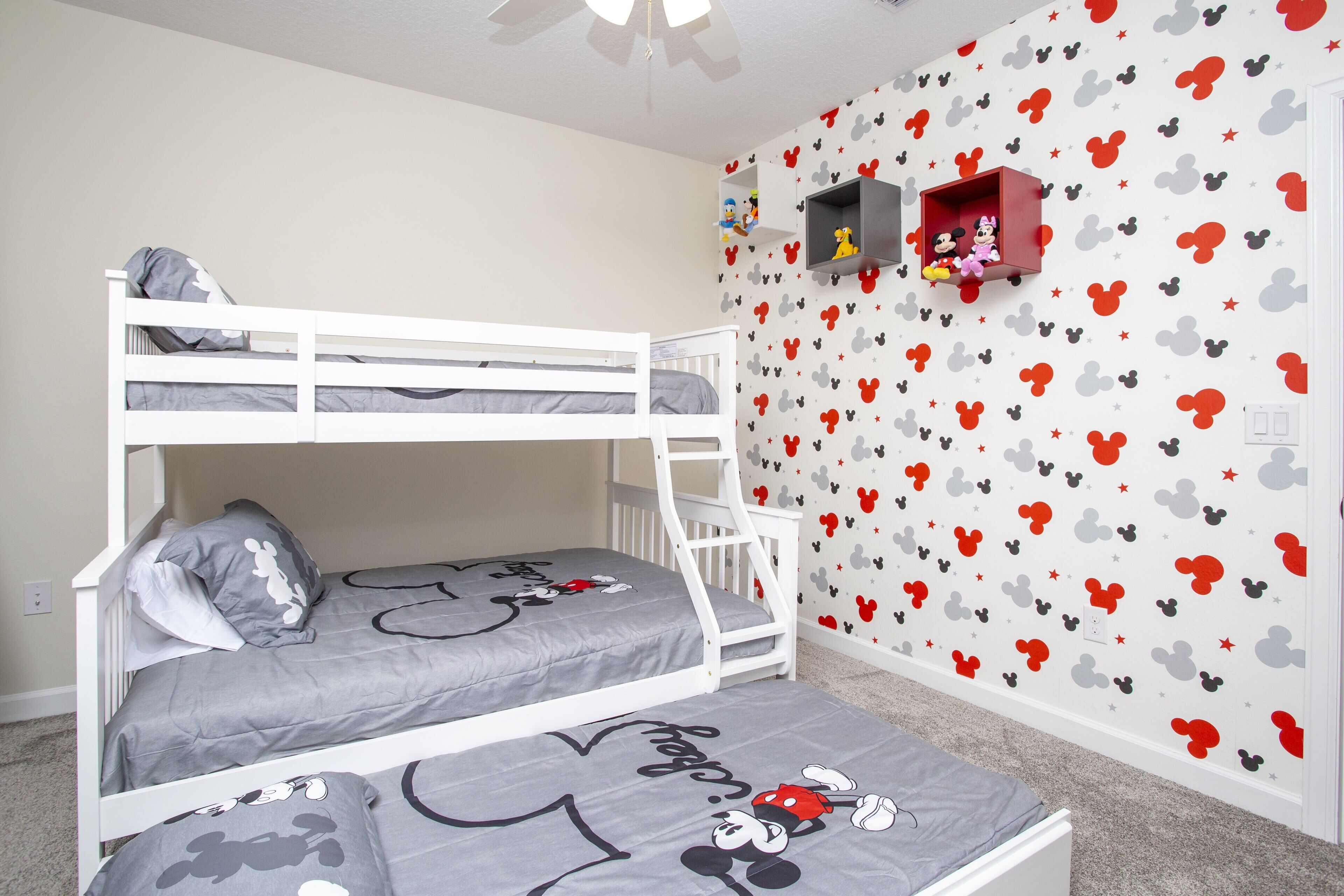 A child’s bedroom with bunk beds, Mickey Mouse themed bedding, and a wall decorated with Mickey Mouse and stars.