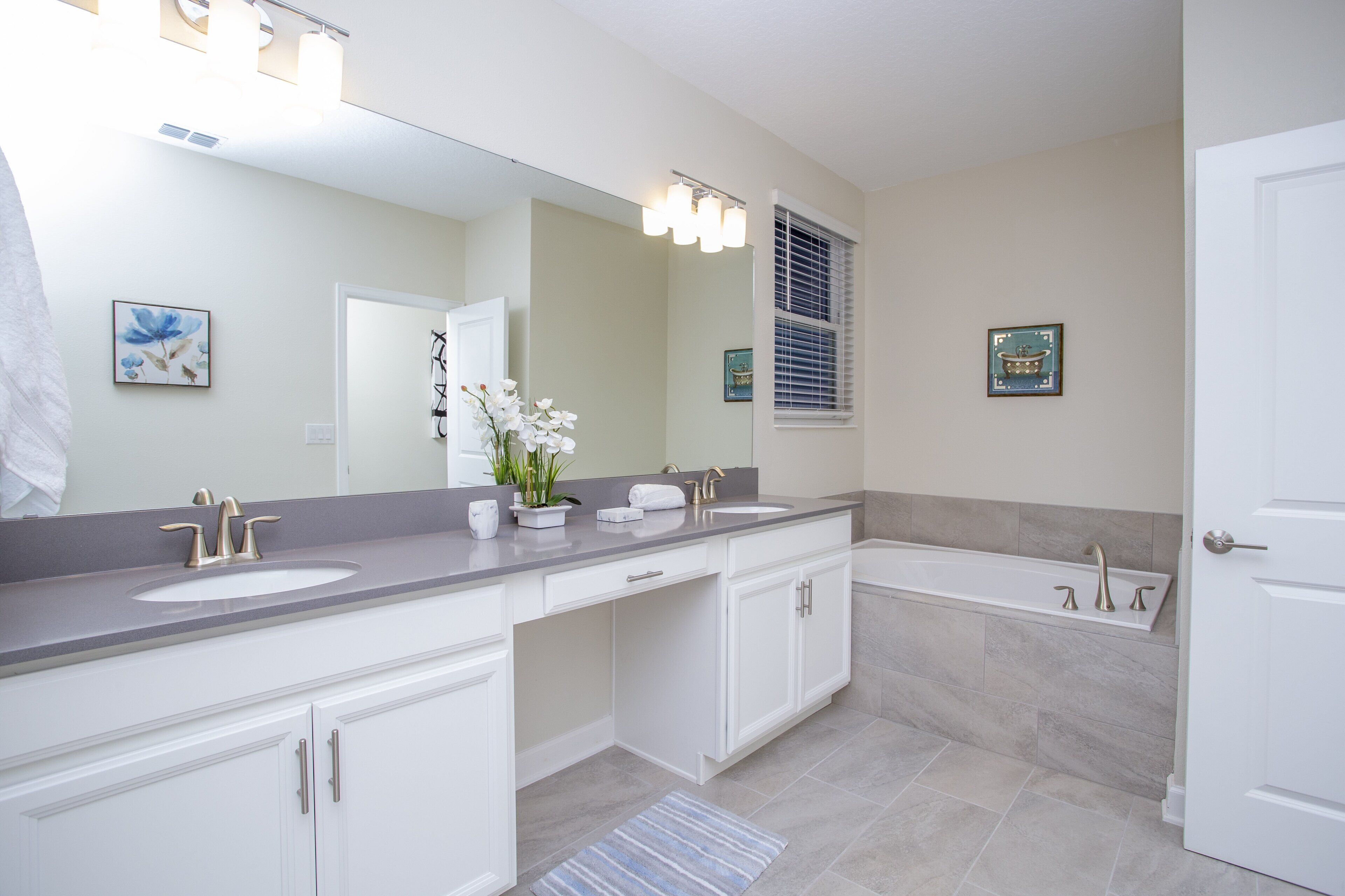 A modern bathroom with two sinks, a bathtub, and a large mirror.