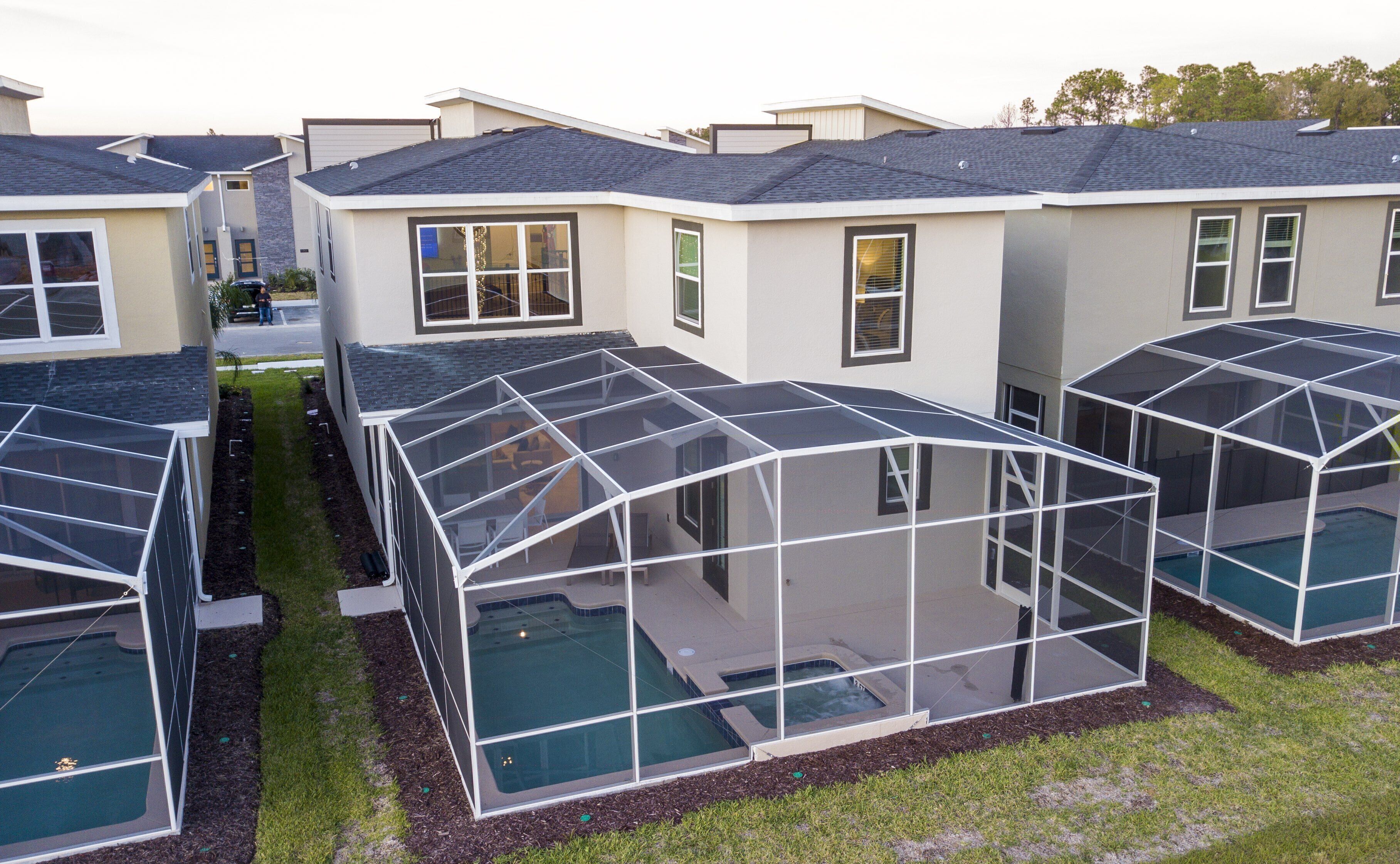 A residential complex with multiple houses featuring large glass-enclosed swimming pools.
