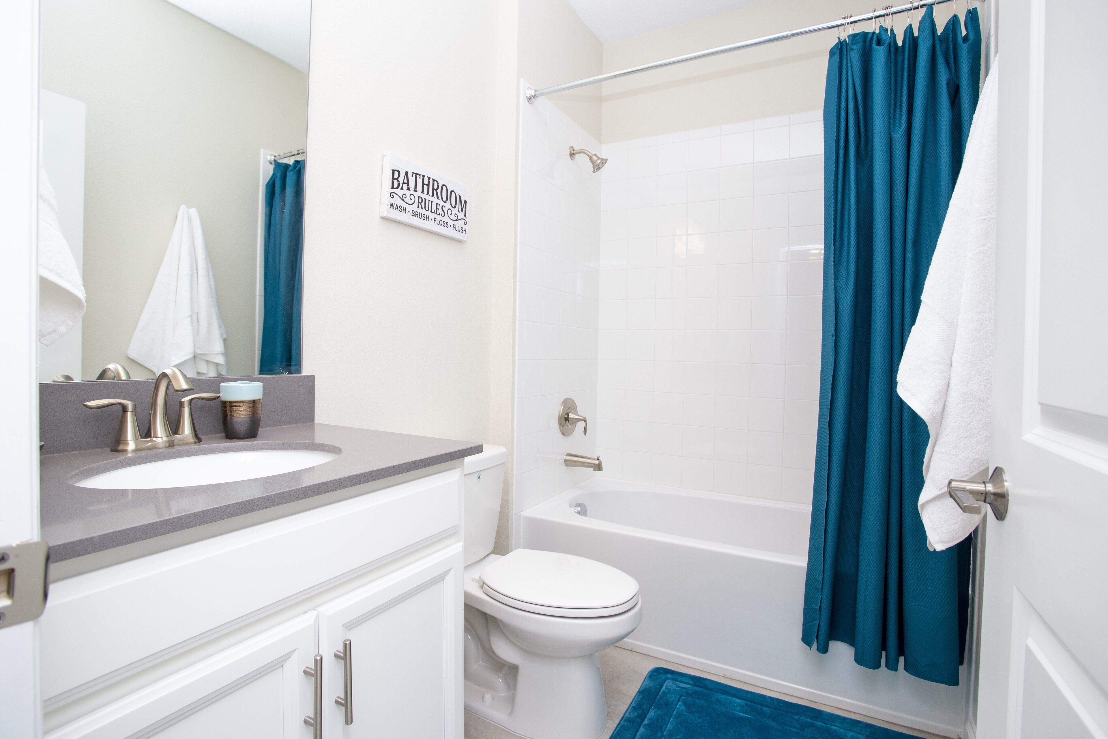 A bathroom with a white sink, a toilet, and a bathtub. There is a blue shower curtain and a white towel hanging on the wall.