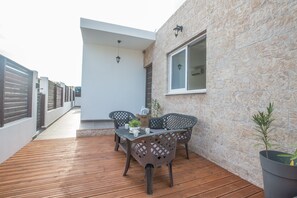 A patio with a wooden deck, a table with chairs, and a potted plant. - Villa Niovi, Beautiful 3BDR Protaras Bungalow with Pool, Close to the Beach (Protaras)