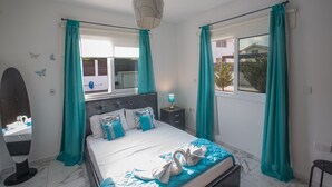 Une chambre à coucher avec un lit, une table de chevet, un miroir et une fenêtre avec des rideaux.