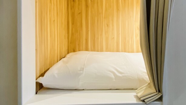 A small, enclosed sleeping area with a wooden wall and a white mattress. - bnb+ Osaka Shinsaibashi - Hostel (Osaka)