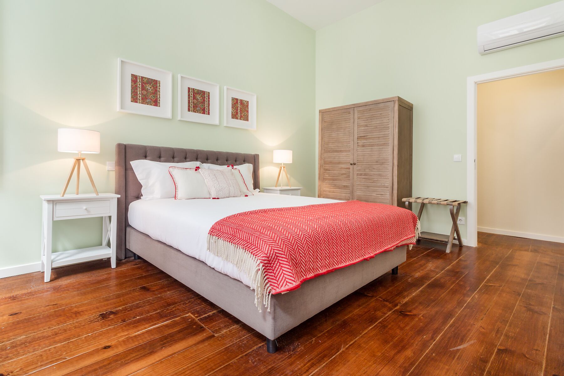 Une chambre à coucher avec un lit, deux tables de chevet, une armoire et une couverture à motifs rouges et blancs.