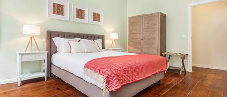A bedroom with a bed, two bedside tables, a wardrobe, and a red and white patterned blanket.