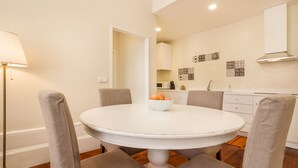 Een eethoek met een ronde tafel, vier stoelen en een schaal fruit.