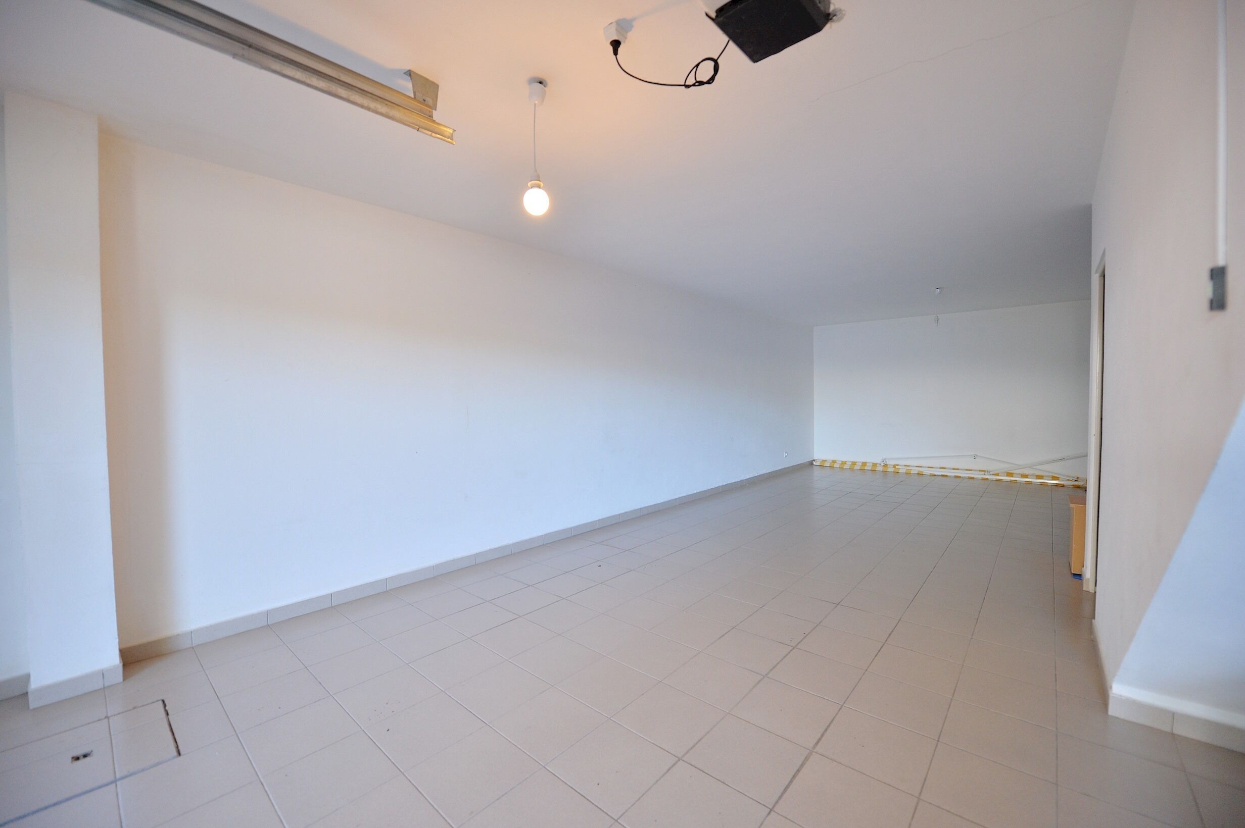 A spacious, empty room with white walls and a tiled floor.