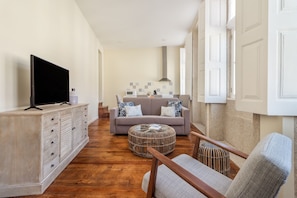Relax in this stylish living room with a flat-screen TV, comfortable sofa, and wicker ottoman.