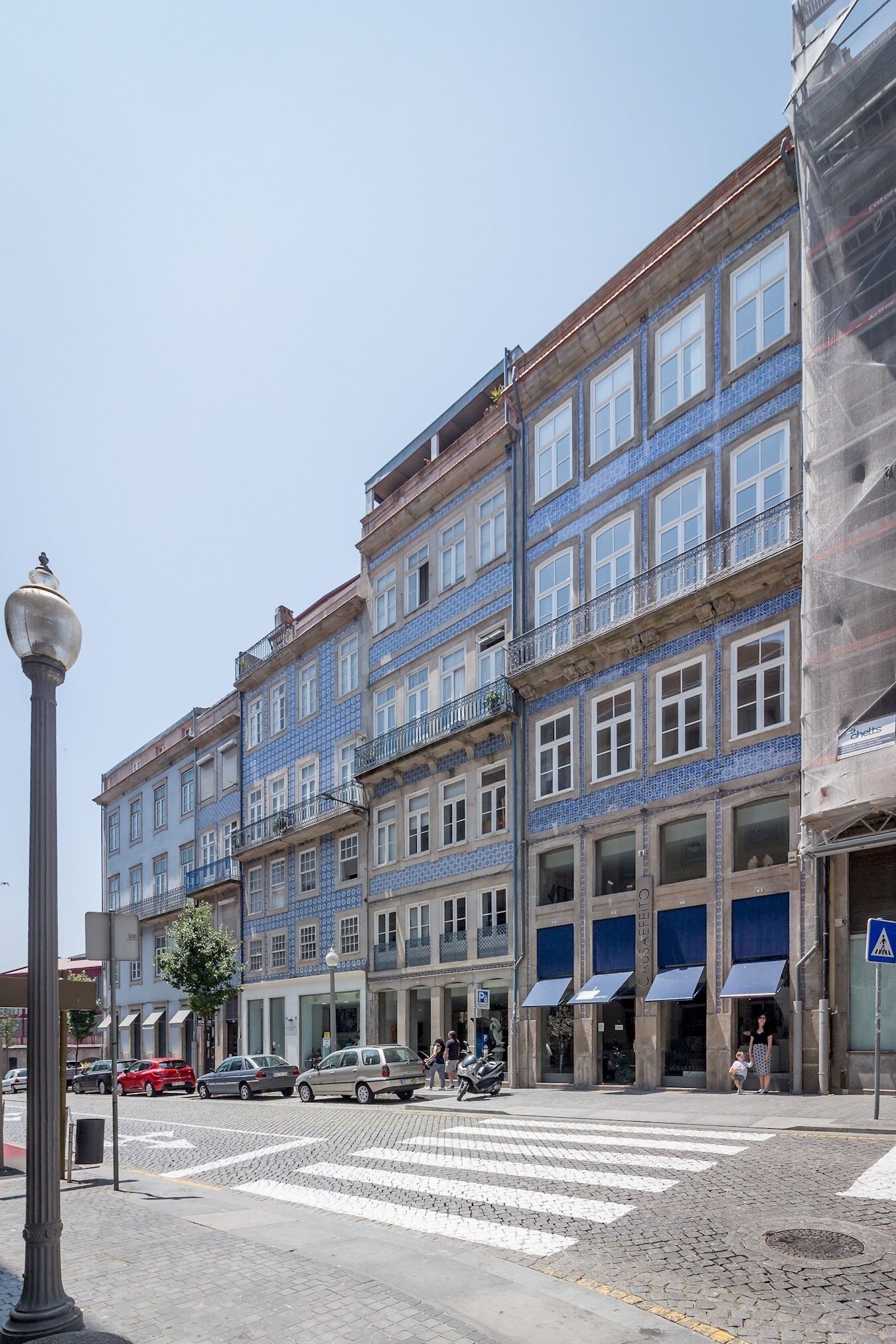 A multi-story building with blue-tiled facades, a pedestrian crossing, and a street lamp.