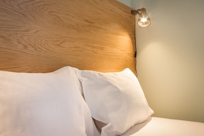 Cozy retreat with a natural headboard and adjustable lamp.