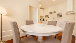 Een eethoek met een ronde tafel, twee stoelen, een fruitschaal en een vloerlamp.