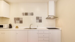 Een moderne keuken met witte kasten, een magnetron, een koffiezetapparaat en een spoelbak.