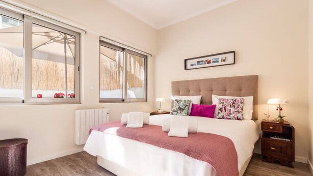 Une chambre avec un grand lit, un radiateur, une fenêtre donnant sur un beau paysage et un tableau encadré au mur.