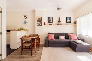 Relax in this stylish living space with a dining area and seating area, featuring a large window, wall art, and comfortable furniture.