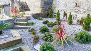 A stone staircase leading up to a building, surrounded by a gravel garden with various plants. - Trind7 · Samasal Trindade Apartments #7 Garden View (Porto)
