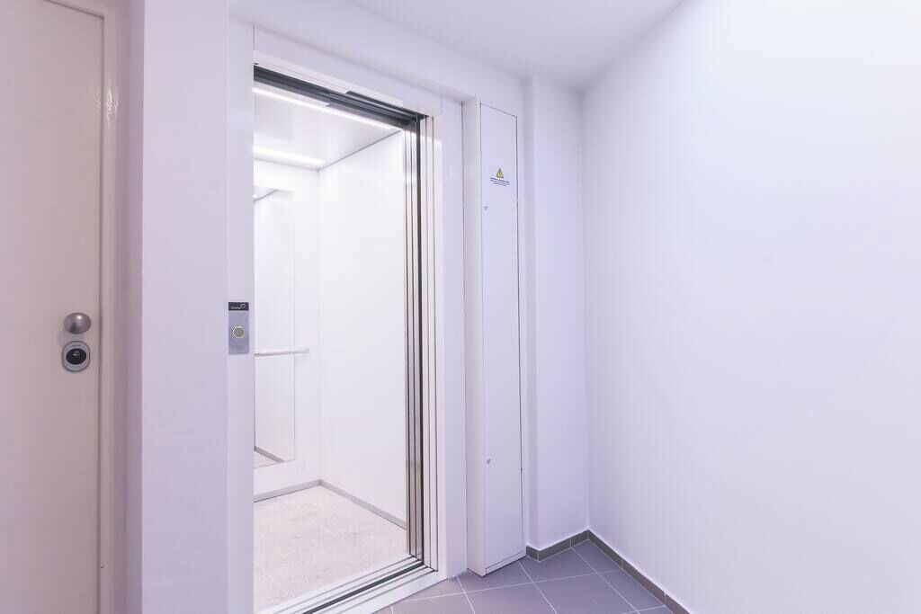 A hotel room with a sliding glass door leading to a bathroom, a white door with a lock, and a tiled floor.