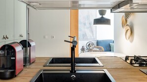 A modern kitchen with a central island, stainless steel appliances, and a view to the living area. - Mat001 · Bohemian Vibe at a Fresh Coastal Getaway (Matosinhos)