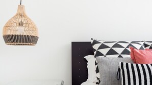 A modern bedroom with a glass bedside table, a black headboard, and a variety of pillows. - Mat001 · Bohemian Vibe at a Fresh Coastal Getaway (Matosinhos)