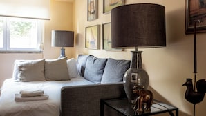 Ein Hotelzimmer mit einem Bett, einer Couch, einer Lampe, einer Vase und Wandbildern.