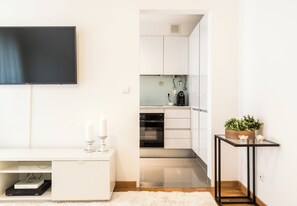Une cuisine moderne avec des meubles blancs, un plan de travail noir et un four encastré.