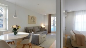 A modern living room with a white sofa, grey armchair, and a dining table with chairs. - Cord04 Blue House Apartment 4 Parking + Super Central (Porto)