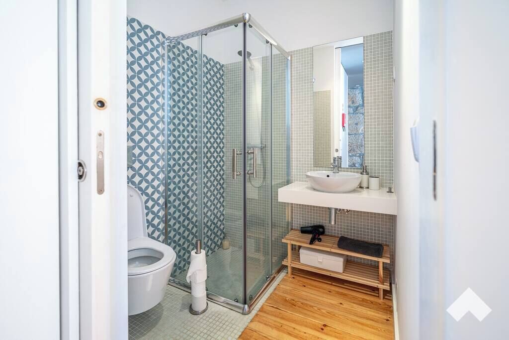 Une salle de bain moderne avec une douche à parois de verre, des toilettes blanches et un meuble-lavabo en bois.