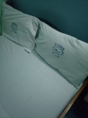 A bed with two pillows, each featuring the logo "Addis Pub." - Addis Lodge (Gilgil)
