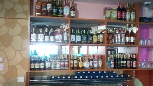 A bar area with shelves of various liquor bottles and glasses. - Addis Lodge (Gilgil)
